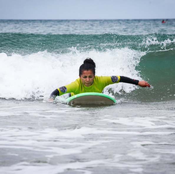 un cours de surf découverte avec surf harmony, apprendre à ramer et glisser allongé, une initiation sur les vagues de la plage de longchamp.